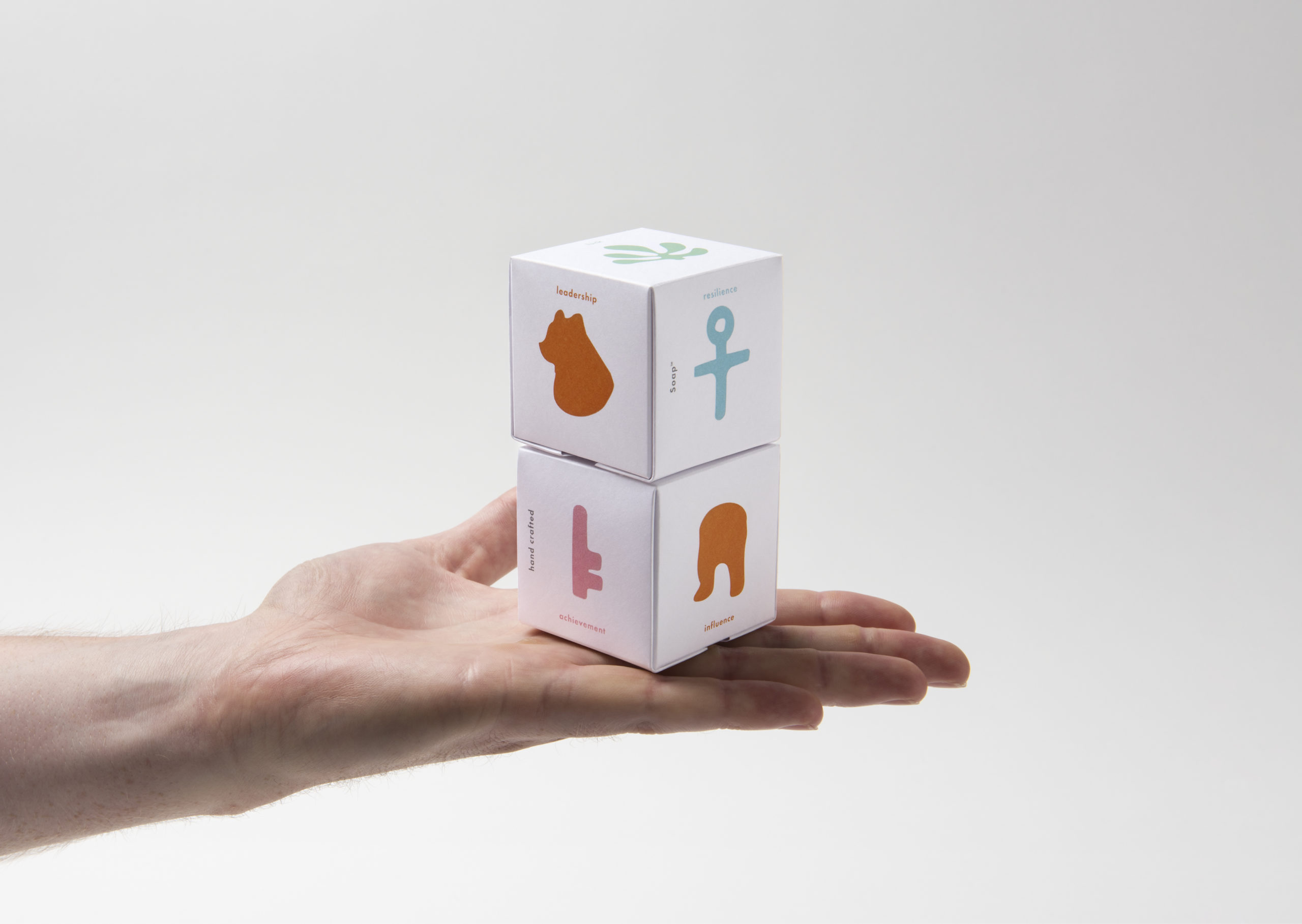 Two stack of beautifully illustrated soap packaging in palm of hand